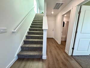 Stairway with wood finished floors and baseboards