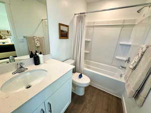 Full bath featuring shower / bath combination with curtain, vanity, and dark wood-type flooring