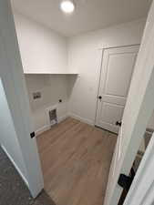 Washroom with light wood-style flooring, hookup for an electric dryer, and hookup for a washing machine