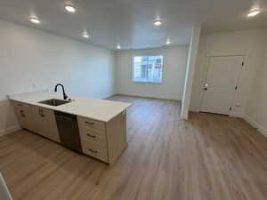 Kitchen featuring a peninsula, dishwasher, light brown cabinetry, open floor plan, and light wood-type flooring