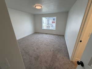 Carpeted empty room with a textured ceiling and baseboards