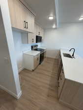 Kitchen featuring modern cabinets, stainless steel appliances, light stone counters, light brown cabinetry, and light wood-type flooring