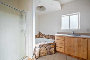 Full bathroom with vanity, a garden tub, a shower stall, and light tile patterned floors
