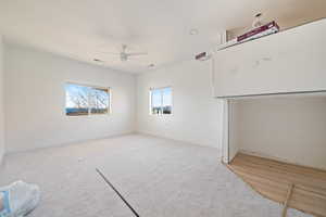 Empty room featuring ceiling fan and light carpet