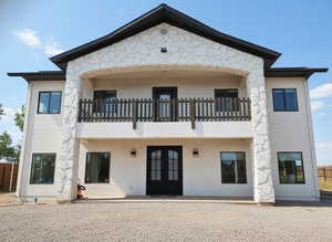 Rear view of property featuring a patio, stucco siding, a balcony, and french doors