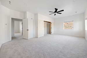 Unfurnished bedroom with light colored carpet and a ceiling fan