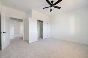 Unfurnished bedroom featuring light carpet, a ceiling fan, and a closet