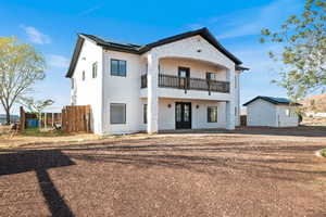 Rear view of house featuring a balcony, french doors, an outbuilding, stucco siding, and roof mounted solar panels