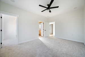 Unfurnished bedroom featuring a ceiling fan, light colored carpet, and ensuite bathroom