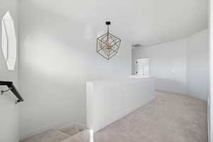 Stairs featuring carpet floors and a chandelier