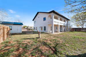 Rear view of property featuring a fenced backyard, a patio area, a balcony, a storage shed, and stucco siding