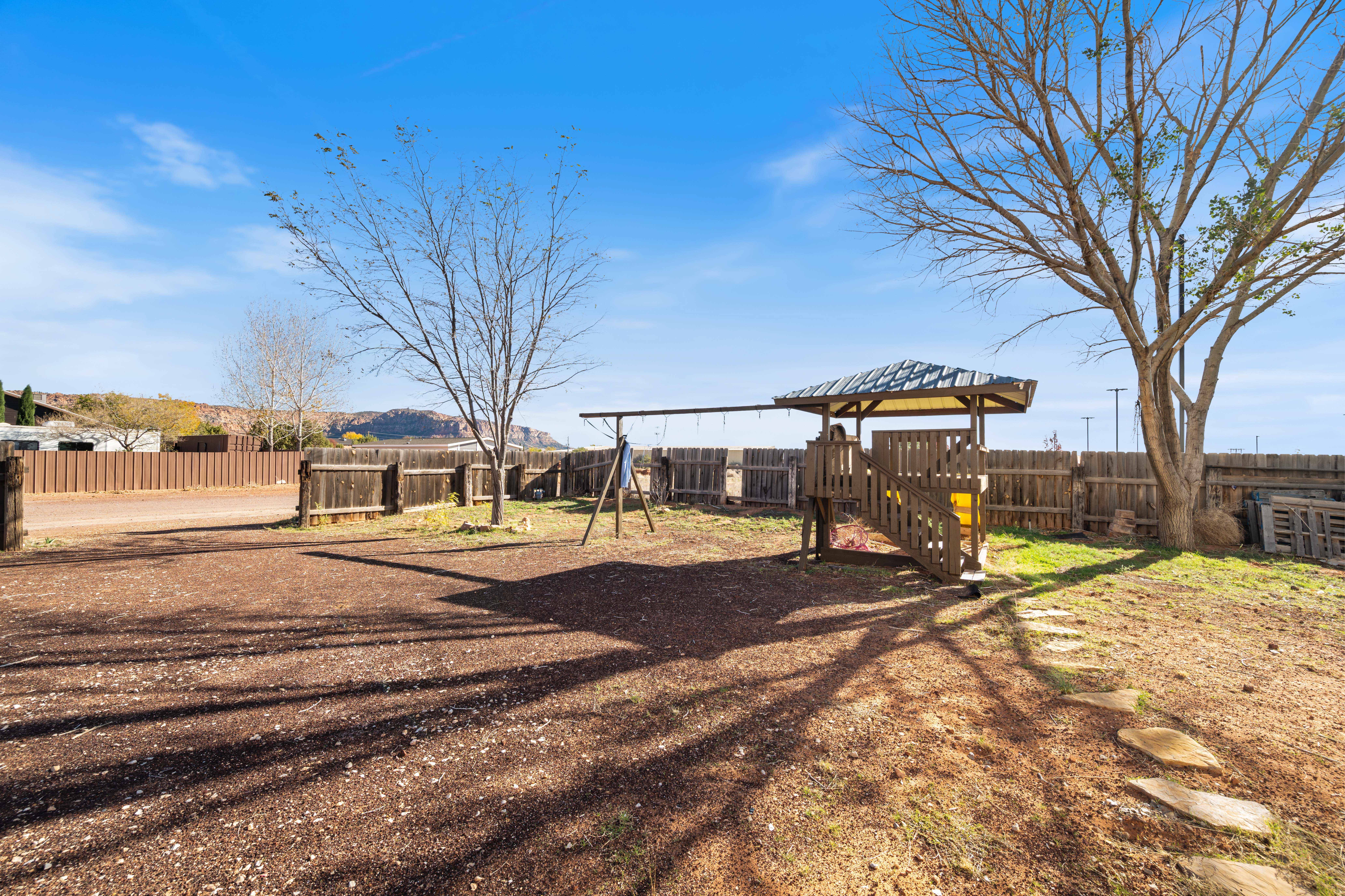 Fenced backyard featuring a playground