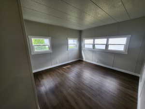Spare room with dark wood-style floors, a decorative wall, and a textured ceiling