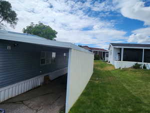 View of green lawn with a sunroom and a carport