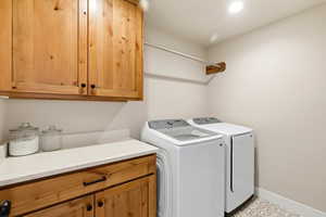 Washroom featuring washer and dryer, cabinet space, and light flooring