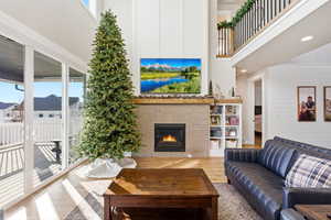 Living area with a high ceiling, a brick fireplace, wood finished floors, and recessed lighting