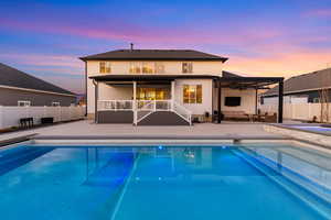 Back of property at dusk featuring a fenced backyard, a patio, an outdoor living space, and ceiling fan