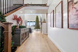 Corridor featuring a high ceiling, light wood-type flooring, wood walls, and stairway