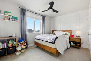Bedroom with a ceiling fan, carpet floors, and a decorative wall