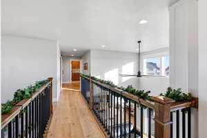 Hallway with light wood-type flooring, recessed lighting, and an upstairs landing