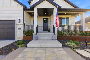 Entrance to property with board and batten siding, stone siding, and a porch
