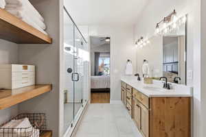 Bathroom with connected bathroom, double vanity, a ceiling fan, light tile patterned flooring, and a shower stall