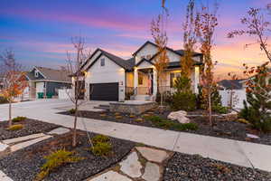 Modern farmhouse featuring board and batten siding, concrete driveway, a garage, and stone siding