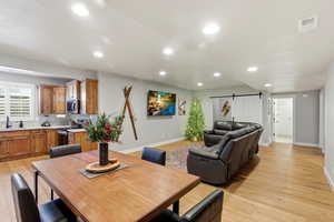 Dining space featuring a barn door, light wood-style flooring, and recessed lighting