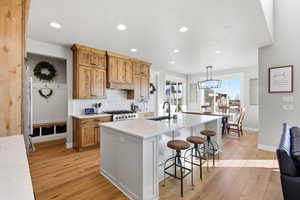 Kitchen featuring backsplash, a kitchen bar, recessed lighting, white cabinets, and light wood finished floors