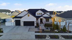 Modern farmhouse featuring board and batten siding, stone siding, a gate, and concrete driveway