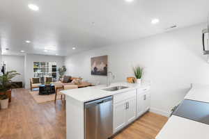 Kitchen featuring a peninsula, appliances with stainless steel finishes, white cabinets, light wood-type flooring, and recessed lighting