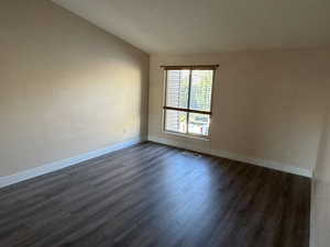 Unfurnished room featuring baseboards and dark wood finished floors