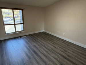 Spare room featuring baseboards and dark wood finished floors