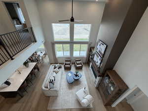 Living room with a high ceiling, ceiling fan, and light wood-style floors