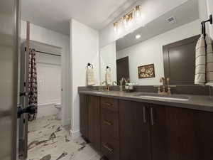 Full bathroom featuring double vanity, shower / tub combo, and light marble finish flooring