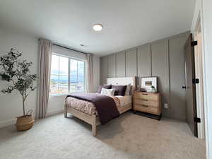 Bedroom featuring light colored carpet and a decorative wall