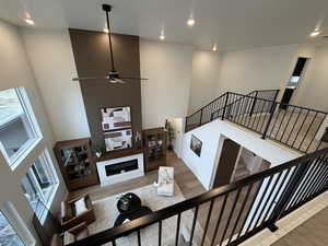 Stairway with a high ceiling, ceiling fan, a fireplace, wood finished floors, and recessed lighting