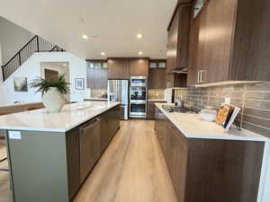 Kitchen with glass insert cabinets, a breakfast bar, backsplash, light wood-style floors, and light stone counters