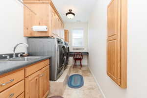 Washroom featuring washer and clothes dryer, cabinet space, and light tile patterned flooring