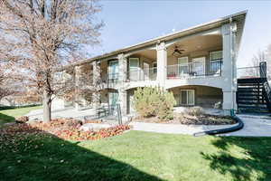 Back of house featuring stairway, a lawn, a ceiling fan, stucco siding, and a porch
