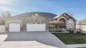 View of front of home with an attached garage, concrete driveway, stucco siding, and stone siding