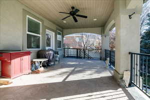 Wooden terrace with ceiling fan, grilling area, and a patio