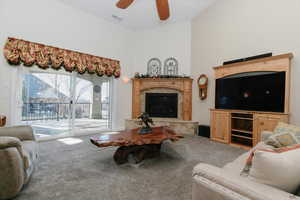 Living area with carpet floors, a high end fireplace, a high ceiling, and a ceiling fan