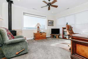 Sitting room featuring a wood stove, ornamental molding, carpet flooring, ceiling fan, and recessed lighting