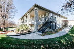 Back of house featuring stairway, a yard, and stucco siding