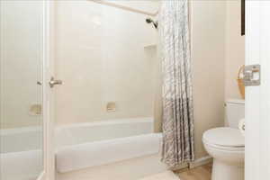 Bathroom with shower / bath combination with curtain and toilet