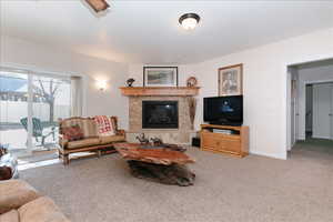 Carpeted living area with a tiled fireplace and baseboards