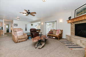Living room featuring carpet flooring, a tiled fireplace, and ceiling fan