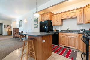 Kitchen featuring black appliances, dark countertops, a breakfast bar, a center island, and hanging light fixtures
