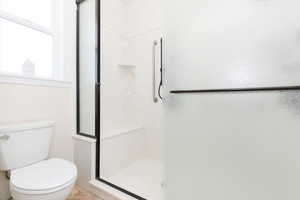 Full bath featuring a shower stall and toilet